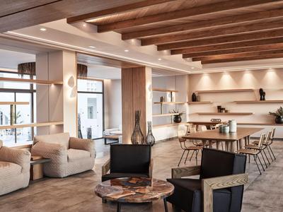 Moderner, heller Hotel-Loungebereich mit Sitzgruppen, Holztischen und dekorativen Elementen.