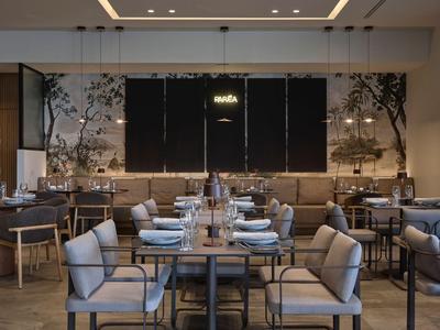 Modernes Restaurant mit gedeckten Tischen und grauen Stühlen in einem hellen, stilvollen Interieur.