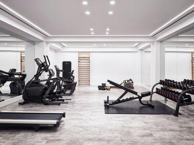 Moderner Fitnessraum mit Laufbändern, Hanteln und Trainingsgeräten in einem Hotel.