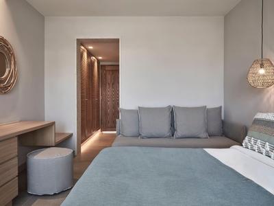Nowoczesny pokój hotelowy z dużym łóżkiem, wygodną sofą i drewnianą komodą.