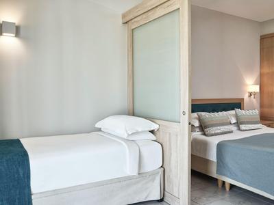 Hotelzimmer mit zwei Betten und einem Trennwand in neutralen Farben und modernem Design.