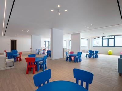 Heller, moderner Raum mit bunten Kindermöbeln und großen Fenstern in einem Hotelspielbereich.