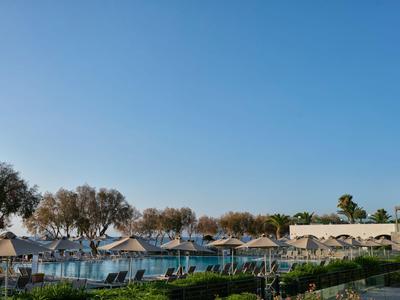 Blick auf einen Hotelpool mit Liegen und Sonnenschirmen unter klarem blauem Himmel