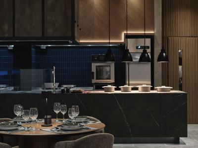 Modern eingerichtete Hotelküche mit dunklem Stein, modernem Ofen und gedecktem Tisch.