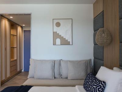 Helles Wohnzimmer mit grauem Sofa, Kissen und abstraktem Wandbild neben Holzwand mit dekorativem Korb.