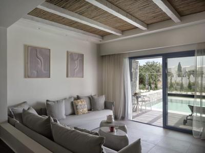 Modernes Hotelzimmer mit gemütlicher Sitzecke und Blick auf den Pool durch große Glasschiebetür.