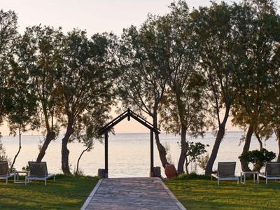 Ein Weg zu einem Pavillon am Wasser mit Bäumen und Liegestühlen auf einem Rasen