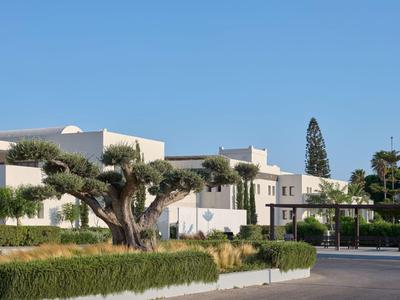 Moderner Hotelkomplex mit weißem Gebäude, Bäumen und klarem blauem Himmel