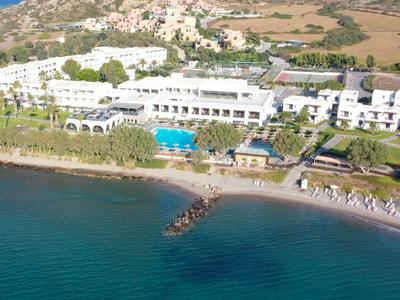 Großes Strandhotel mit Pool und Liegestühlen direkt am Meer in einer ländlichen Gegend.