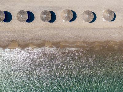 Veduta aerea di ombrelloni sulla spiaggia con acqua calma e onde delicate.