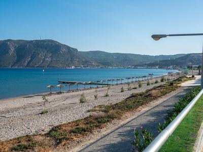 Passeggiata sulla spiaggia con spiaggia di ciottoli, molo e montagne sotto un cielo limpido
