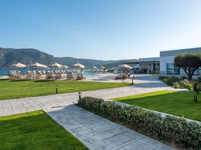Area hotel moderna con piscine, lettini e montagne sullo sfondo sotto un cielo limpido.