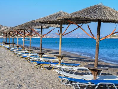 Fila di ombrelloni e lettini sulla spiaggia sabbiosa con vista sul mare.