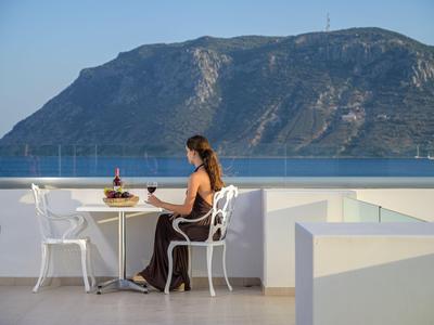 Donna seduta a un tavolo su una terrazza con vista su una montagna e il mare.