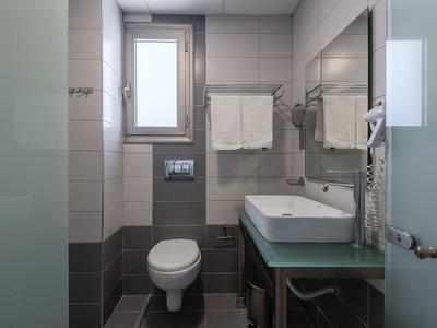 Bagno moderno con WC, lavabo, specchio, portasciugamani e asciugacapelli.