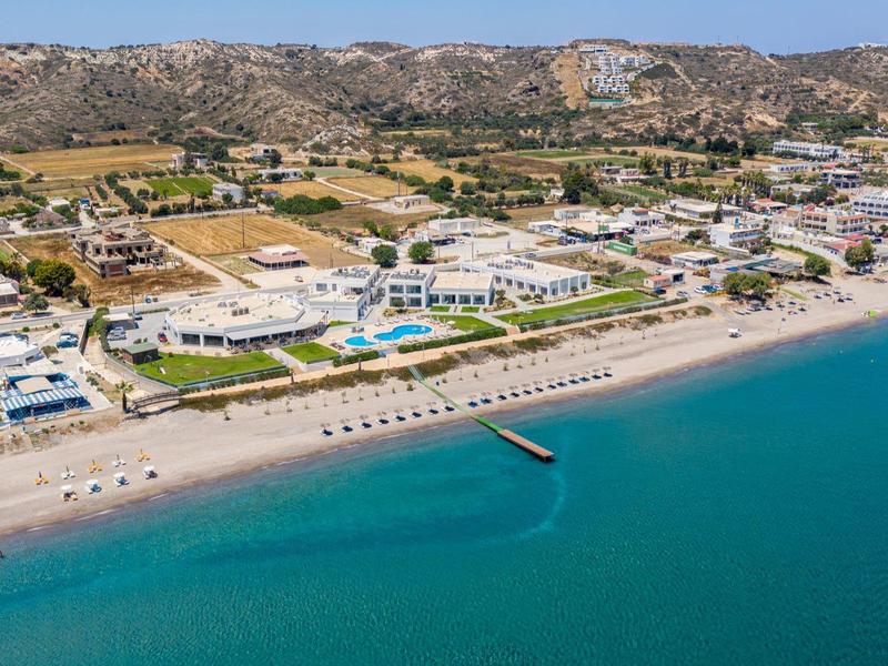 Veduta aerea di una spiaggia con hotel e acqua limpida e blu lungo la costa.