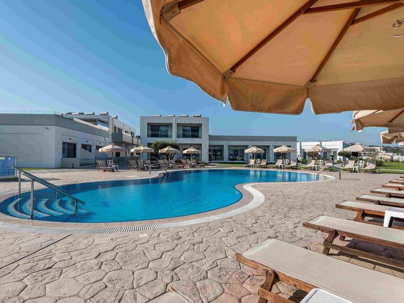 Grande piscina con lettini e ombrelloni in una località di vacanza soleggiata.