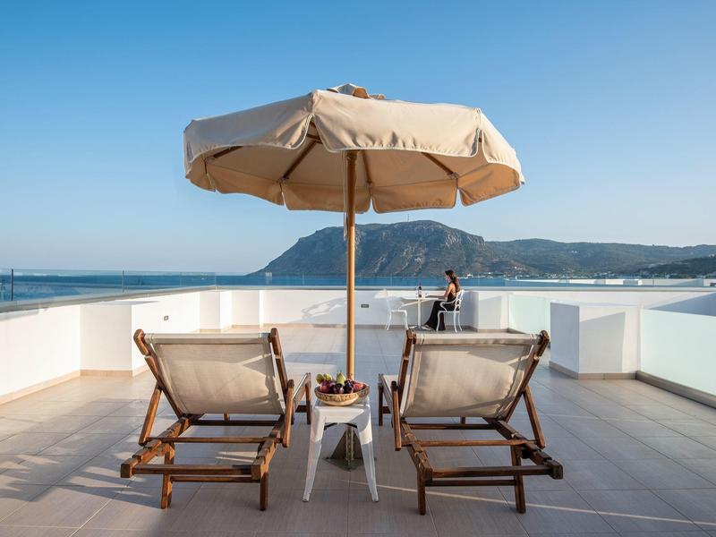 Due sedie a sdraio con ombrellone su terrazza con vista mare e cielo sereno.