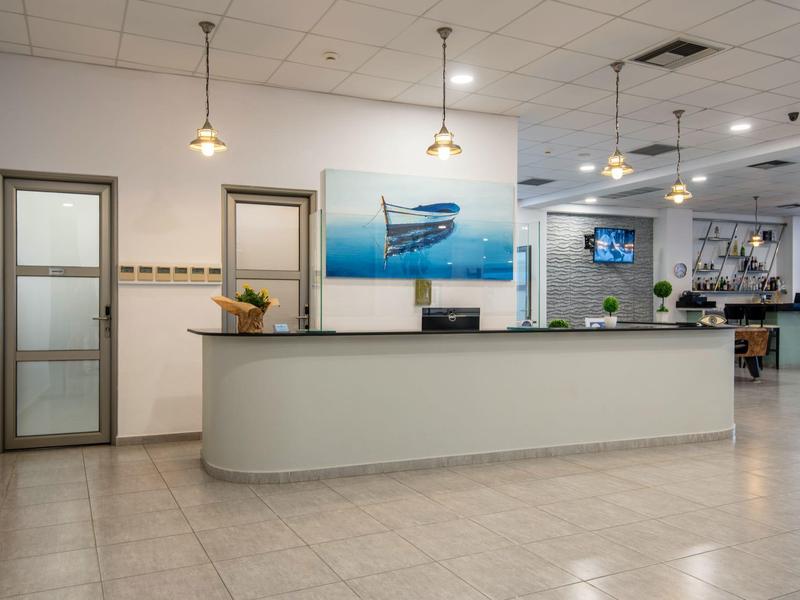 Area di ricevimento luminosa con bancone lungo, due porte, immagine di barca e luci moderne a soffitto.