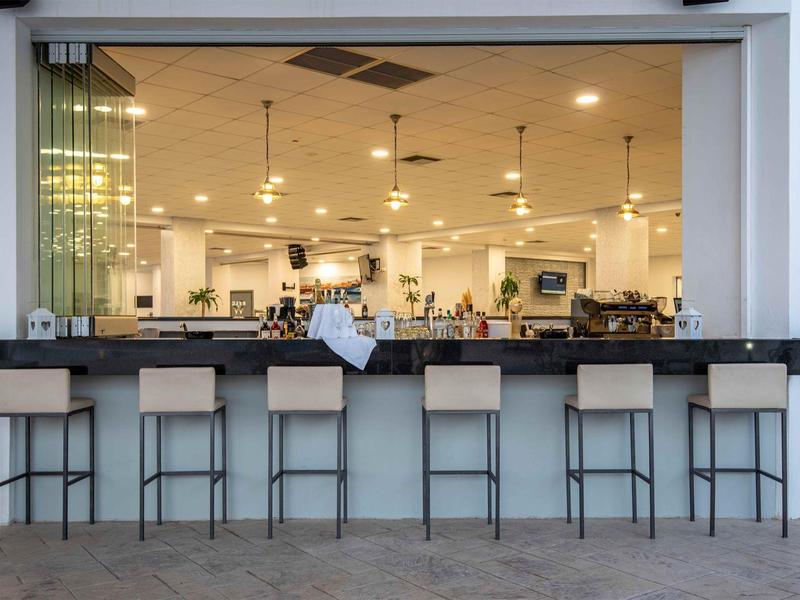 Area bar moderna in hotel con sette sgabelli e bancone aperto.