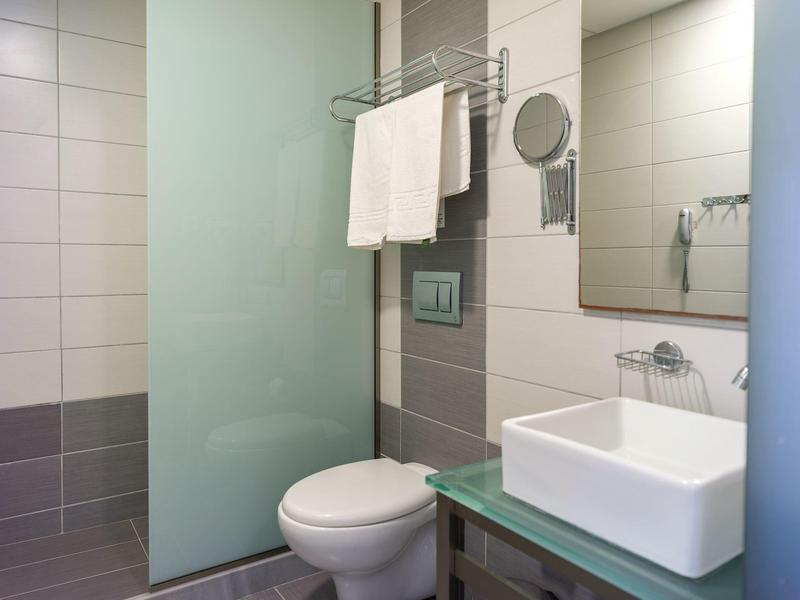 Bagno pulito con WC, lavabo e doccia in vetro con asciugamani.