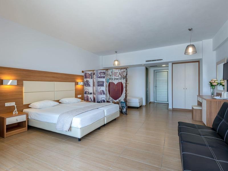 Camera d'hotel moderna con letto matrimoniale, divano, scrivania e parete divisoria decorativa.