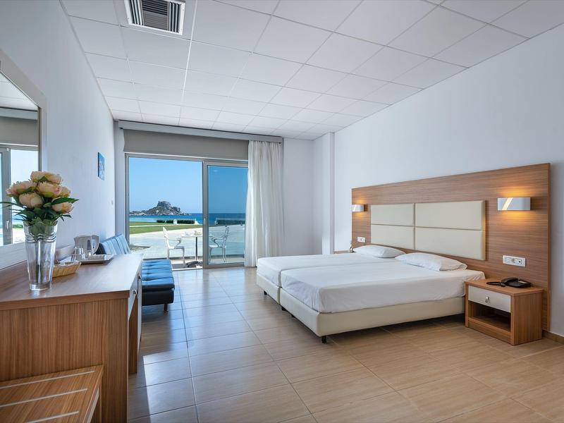 Camera d'hotel luminosa con balcone e vista mare.