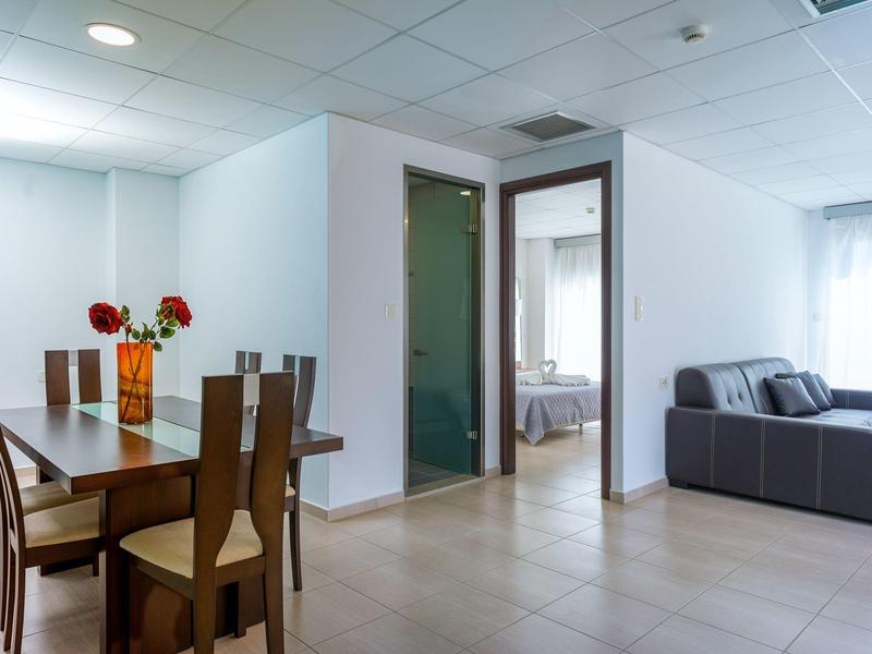 Zona giorno moderna con tavolo da pranzo, sedie, divano e vista sulla camera da letto.