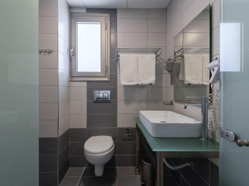 Bagno moderno con WC, lavabo, specchio, portasciugamani e asciugacapelli.