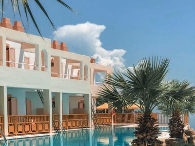 Hôtel avec piscine, rambarde en bois et palmiers sous un ciel clair