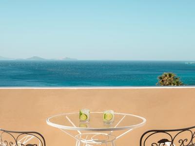 Terrasse avec verre et boissons avec vue sur la mer et ciel bleu clair.