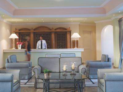 Réception d'hôtel avec réceptionniste et espaces de détente modernes dans une pièce lumineuse et élégante.