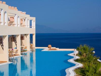 Piscine à débordement dans un hôtel avec vue sur la mer bleue et des palmiers.