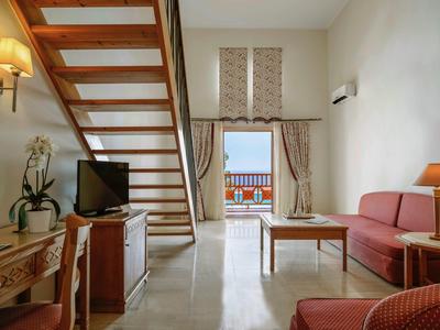 Espace de vie avec escalier, canapé, télévision et vue sur un balcon avec vue sur la mer.