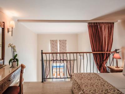 Chambre confortable avec balcon, rideaux rouges et commode en bois dans une chambre d'hôtel.