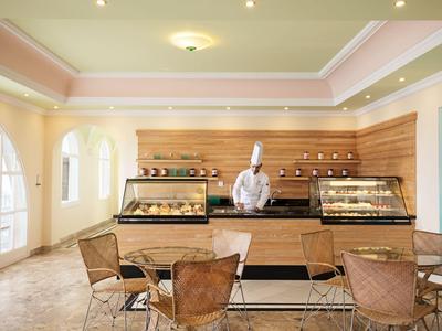 Hotelbuffet mit Glasvitrinen, Sitzgelegenheiten und Koch in weißer Uniform.