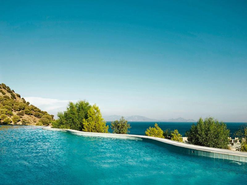 Piscine à débordement avec vue sur l'océan et ciel bleu clair par jour ensoleillé.