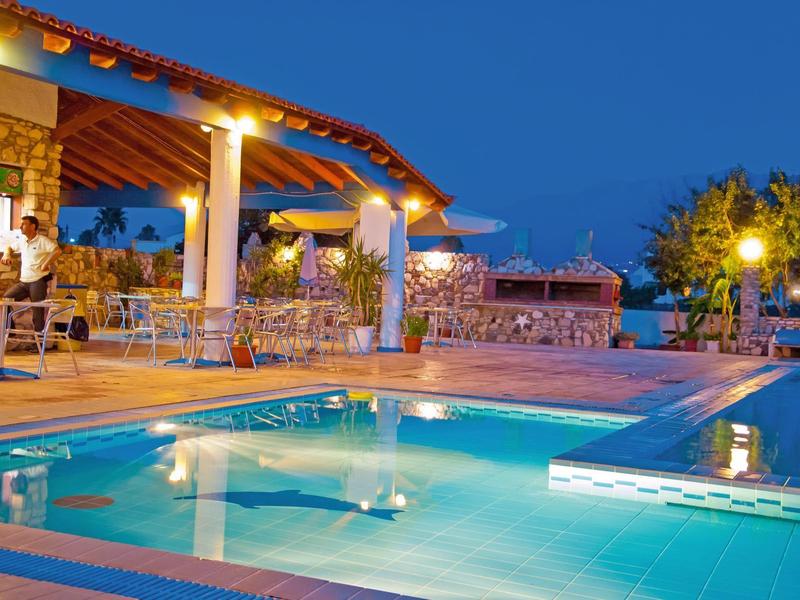 Beleuchteter Außenpool mit Sitzbereich und Dachterrasse bei klarem Nachthimmel.