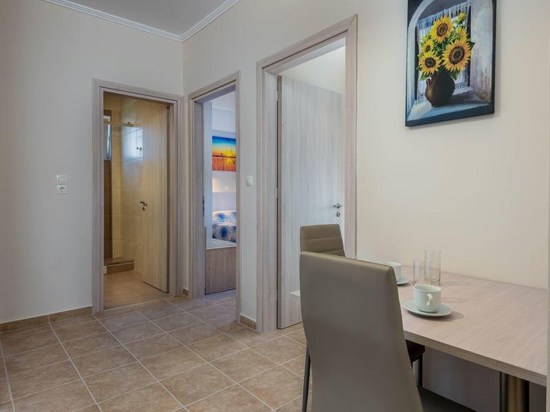 Kleiner Essbereich mit Tisch, zwei Gläsern und Stuhl, Flur mit Türen und hellem Wandbild.