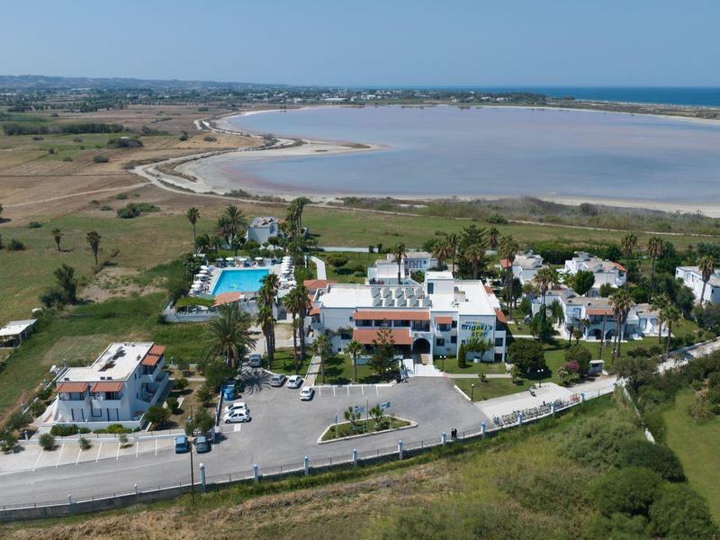 Kleines Dorf mit weißen Häusern am Ufer eines weiten Sees unter blauem Himmel.