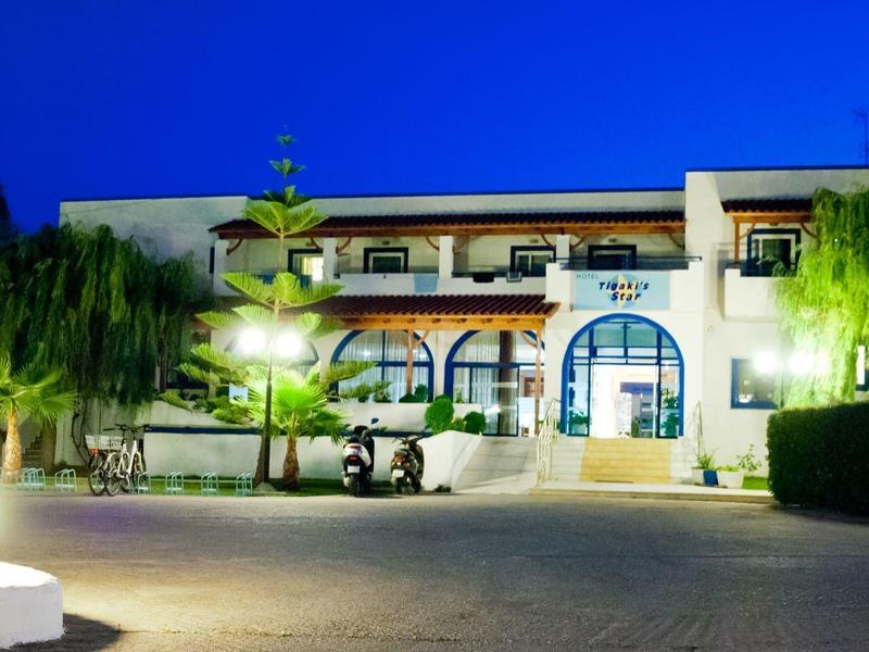 Ein hell beleuchtetes, zweistöckiges Gebäude bei Nacht mit Bäumen und einem golfcart davor.