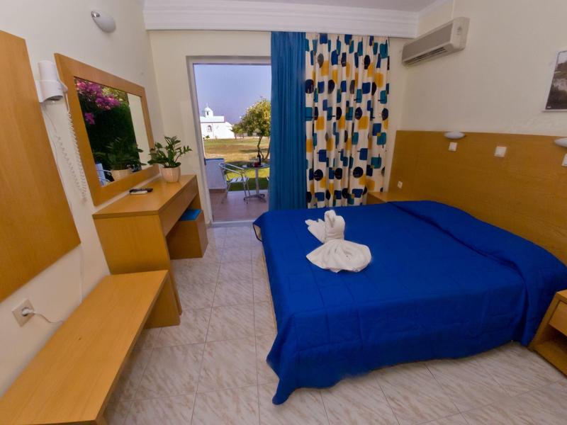 Einfarbig blaue Bettdecke im Zimmer mit Holzmöbeln und Balkon mit Bergblick.