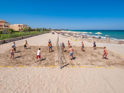 Menschen spielen Volleyball an einem langen Strand mit Hotelgebäuden im Hintergrund