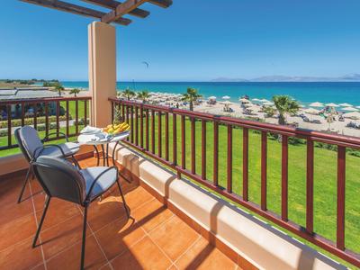 Balcone con sedie e tavolo con vista sul mare e lettini sulla spiaggia.