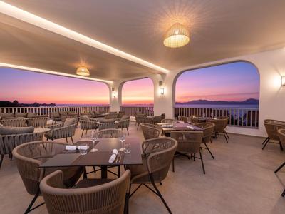 Terrazza dell'hotel con aree salotto e vista al tramonto sul mare.