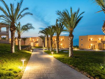 Sentiero illuminato fiancheggiato da palme che conduce a un edificio dell'hotel al crepuscolo.