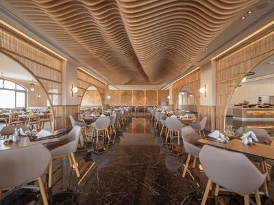 Ampia sala da pranzo moderna con mobili in legno e soffitto ondulato in toni caldi.