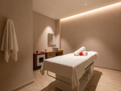 Stanza massaggi semplice con lettino confortevole e illuminazione indiretta calda.