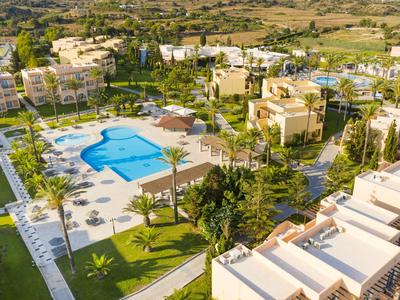 Vogelperspektive eines Hotels mit großem Pool, Liegestühlen und grünen Gärten.