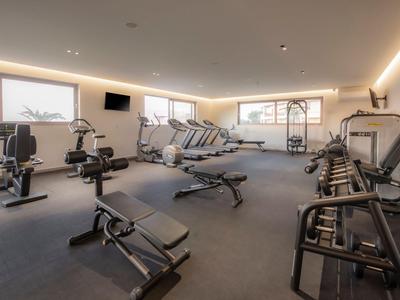 Moderner Fitnessraum mit verschiedenen Trainingsgeräten und großen Fenstern